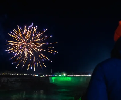 Spectacular nighttime view of fireworks illuminating Niagara Falls during the Winter Festival of Lights, capturing the magic and wonder that draws visitors from around the world