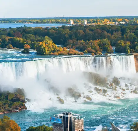 Close-up autumn view of the majestic American Falls with its powerful cascades tumbling over the rocky cliff face, surrounded by fall foliage