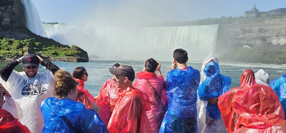 Group of tourists enjoying Maid of the Mist boat ride at Niagara Falls with spectacular waterfall views