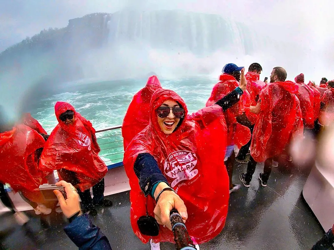 Tourist using selfie stick to capture the incredible mist experience on Niagara City Cruises boat