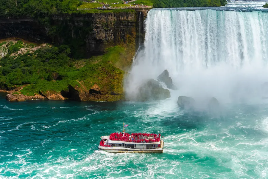 Niagara City Cruises boat approaching the Falls with a rainbow in the autumn mist