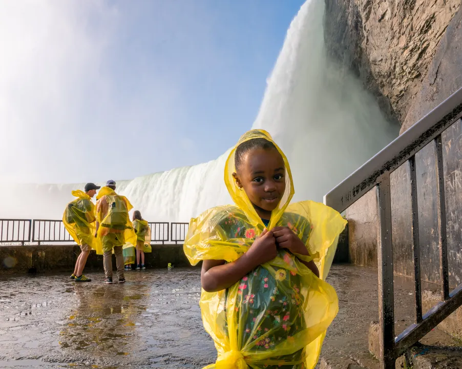 Child in bright yellow poncho enjoying the Journey Behind the Falls tunnel experience