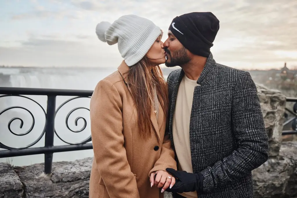 Romantic couple kissing at Niagara Falls with autumn foliage