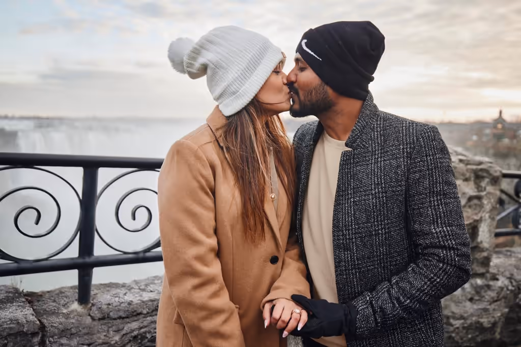 Romantic couple kissing at Niagara Falls with autumn foliage