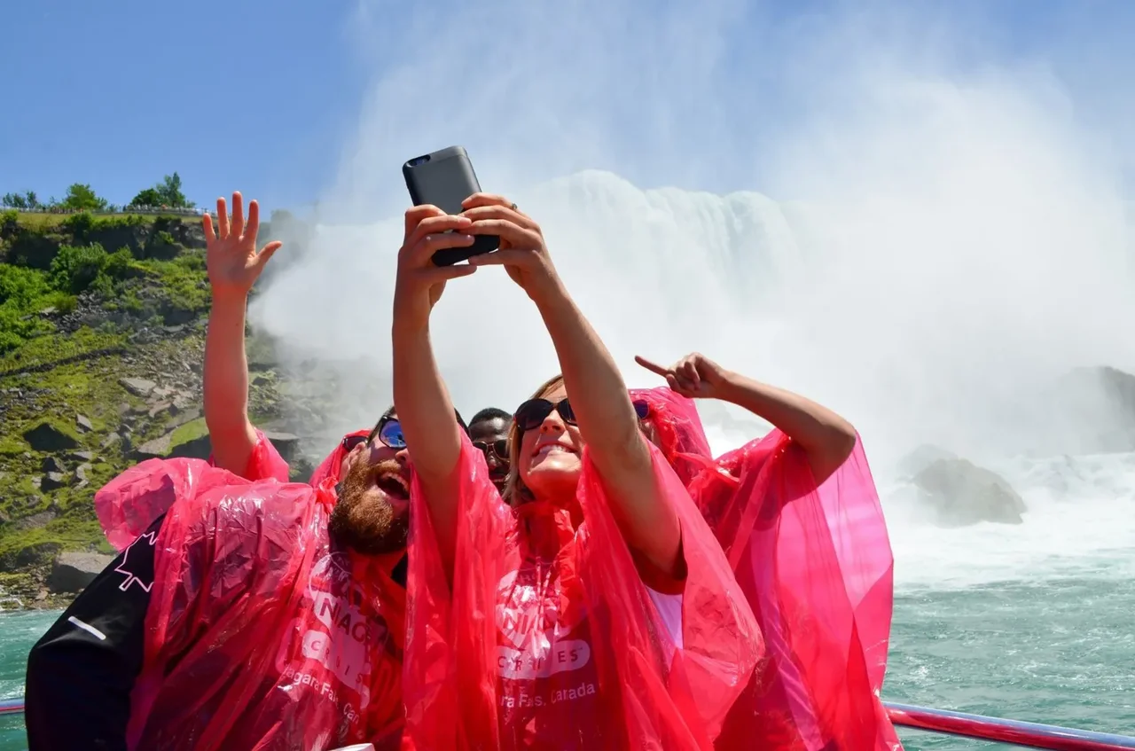 Friends taking a selfie aboard Niagara City Cruises with mist in the background