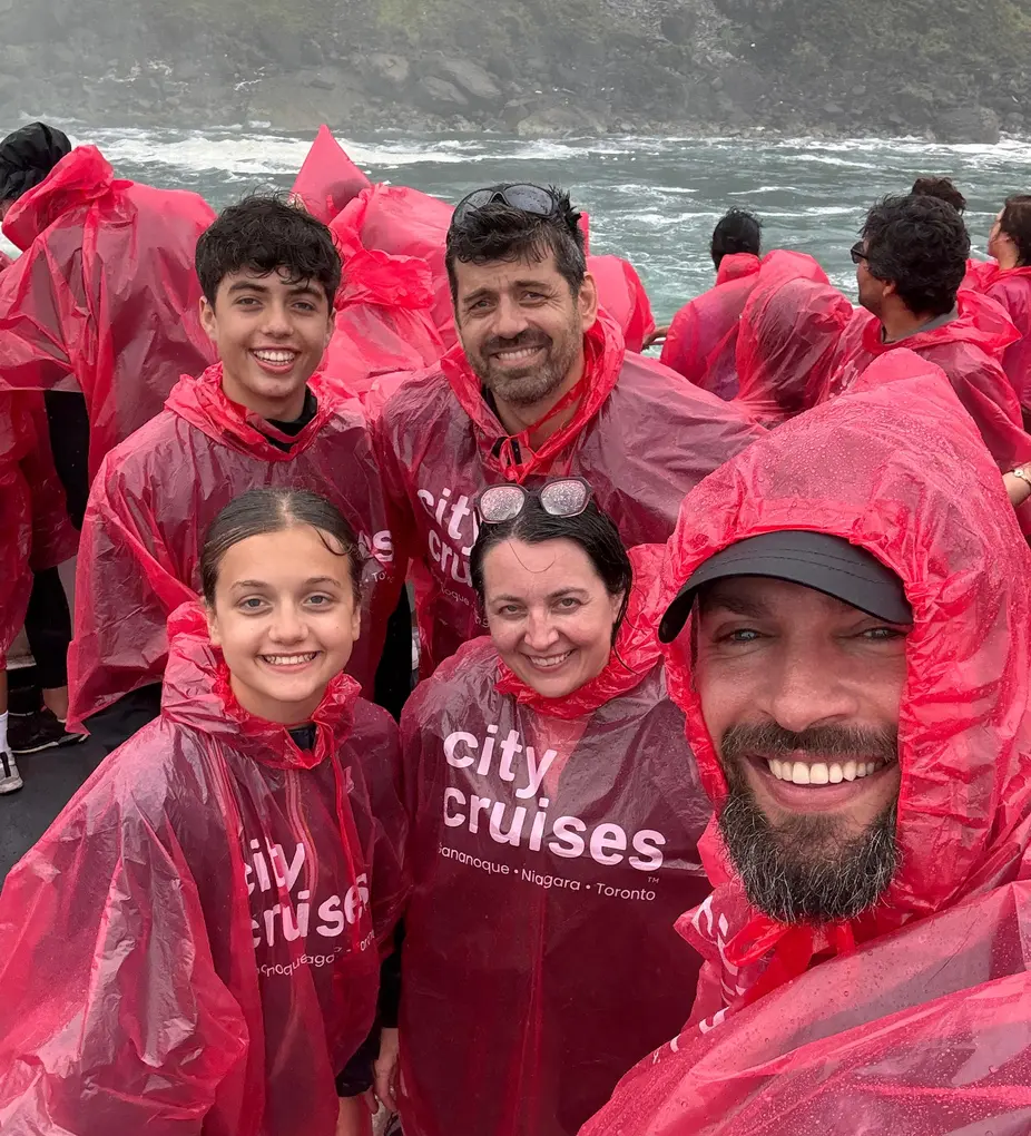 Happy family enjoying the mist and excitement aboard the Niagara City boat cruise wearing complimentary ponchos