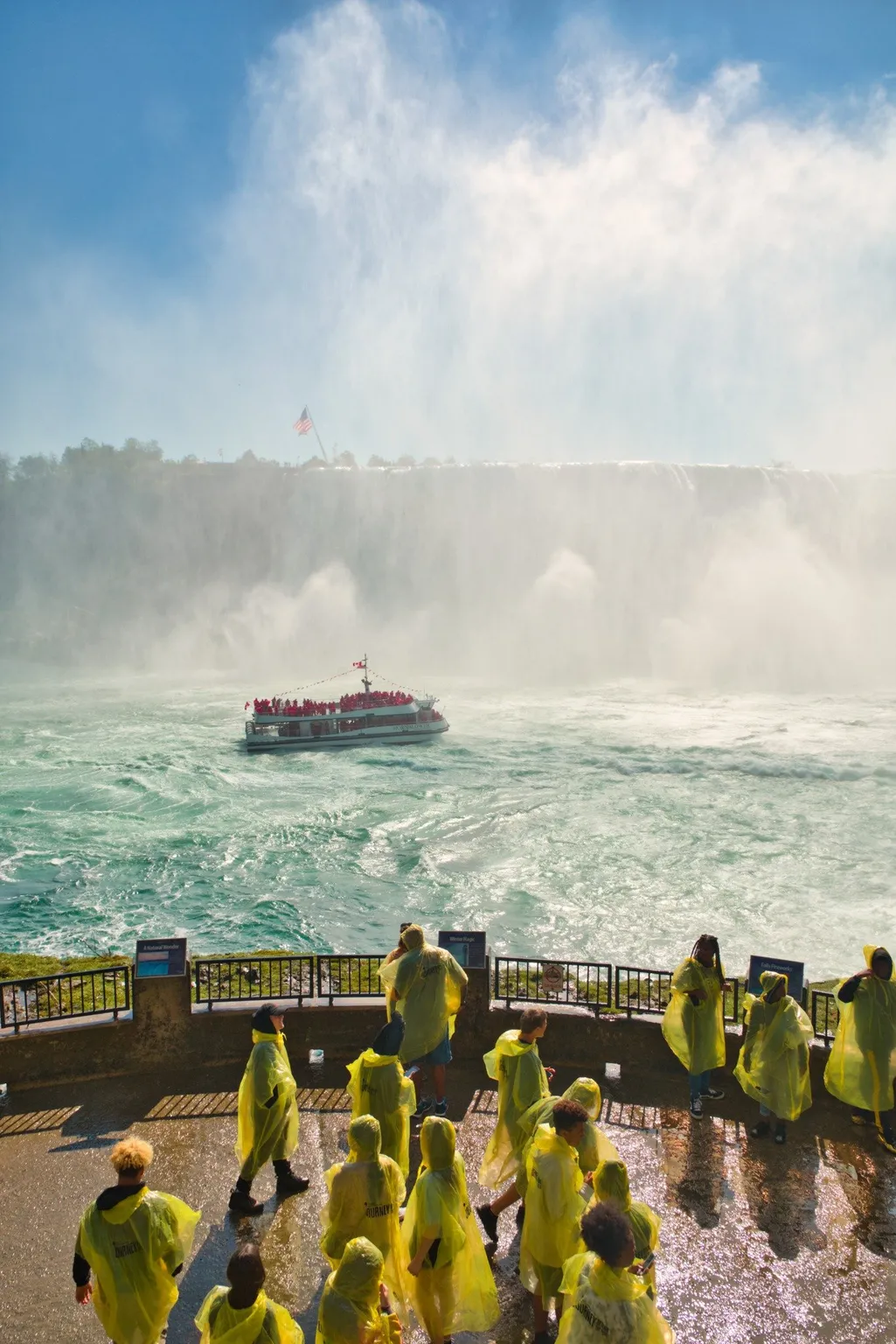 Tourists enjoying scenic views while waiting on shore for their Niagara City Cruises boat departure