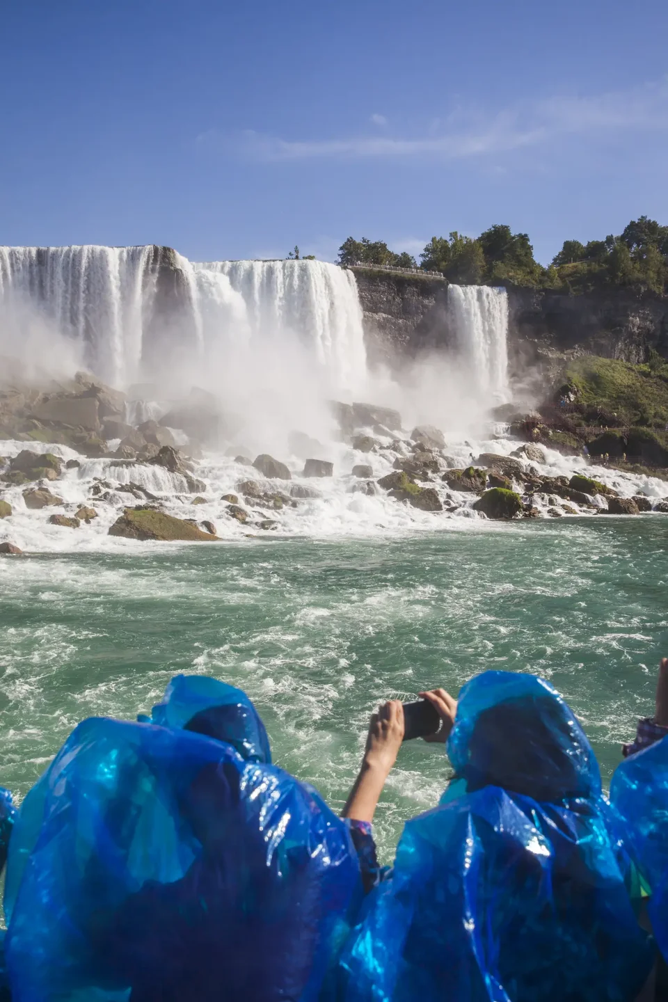 Tourists taking photos while on Maid of the Mist boat approaching Niagara Falls